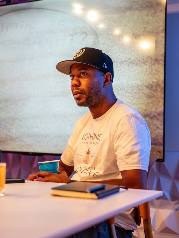 Man wearing a black hat and white t-shirt in a podcast studio