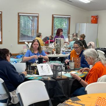 Group of people crafting at tables indoors.