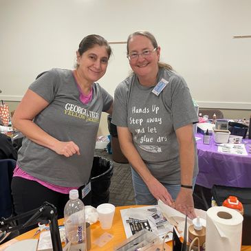Two women smiling at a crafting table.