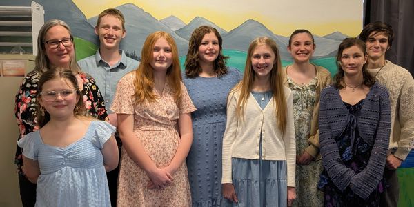 Group of nine smiling people standing together indoors.