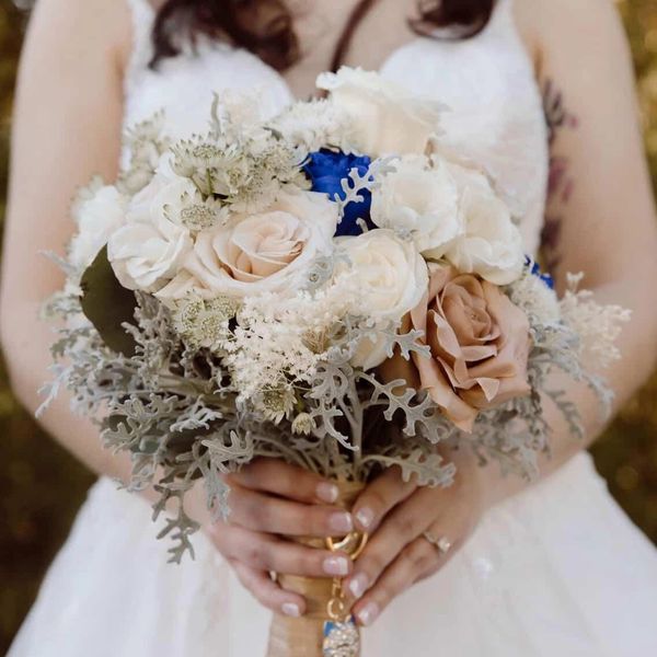 Modern bridal bouquet with ivory and blush roses, soft greenery, and subtle blue accents