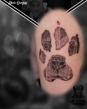 Detailed dog paw print memorial tattoo incorporating a realistic dog portrait by Dave Sanders at Ren