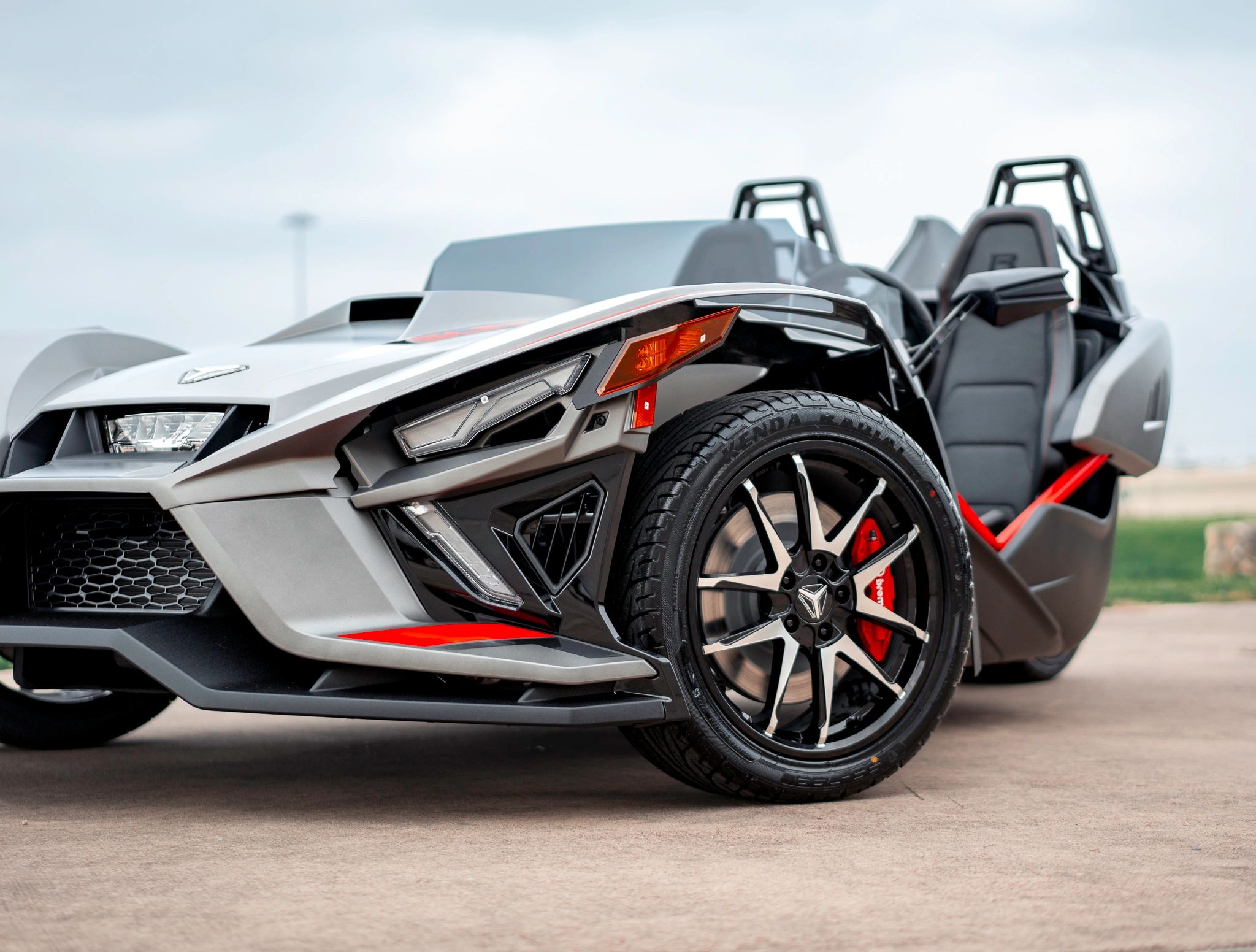 Silver and black Polaris Slingshot parked outdoors with both seats visible