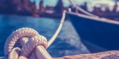 A wooden boat of black anchor with a rope at marina port gouves