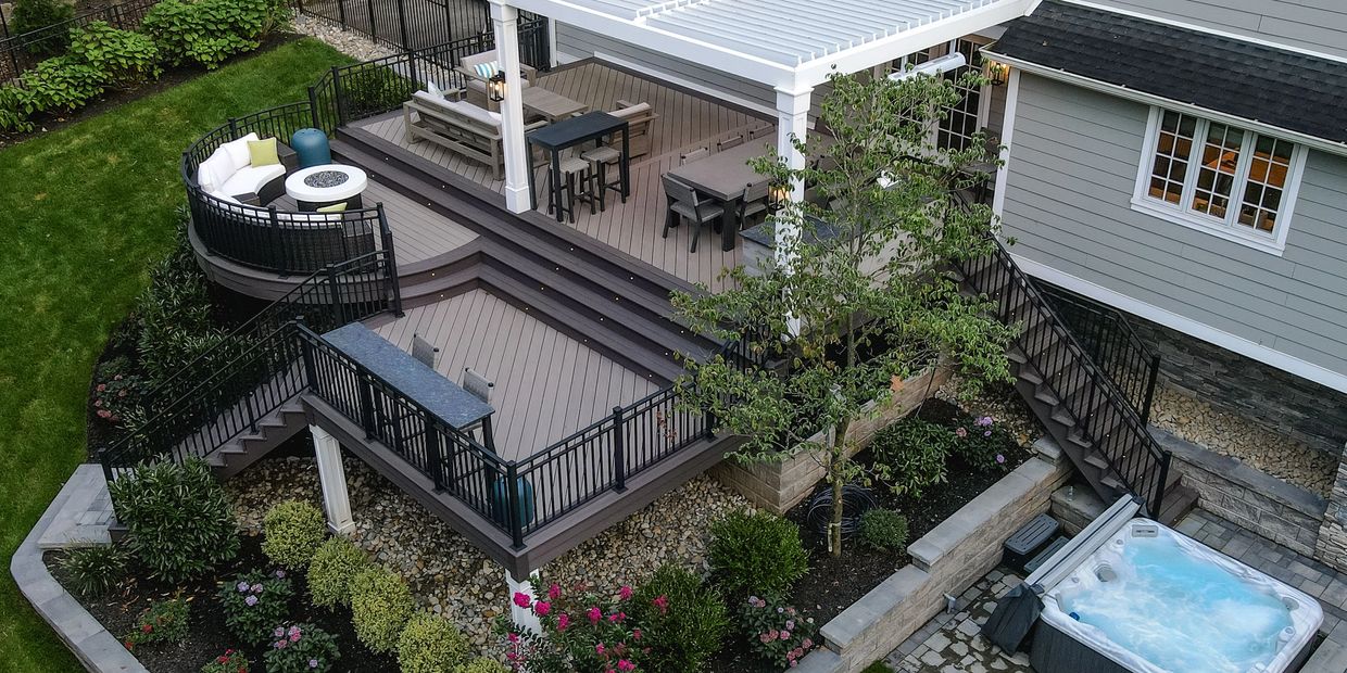 A modern multi-level backyard deck with seating, dining, and a hot tub.