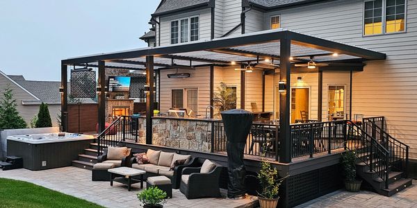 Modern backyard patio with seating, lighting, and a hot tub at dusk.