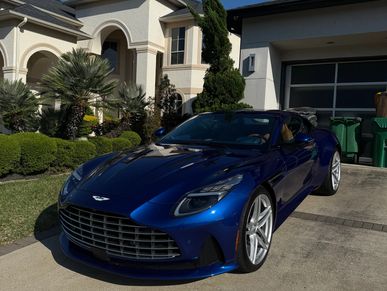 Blue Ashton Martin DB11 sitting in a driveway.