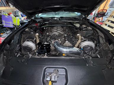 Twin turbocharged engine setup in a car with polished intake piping.