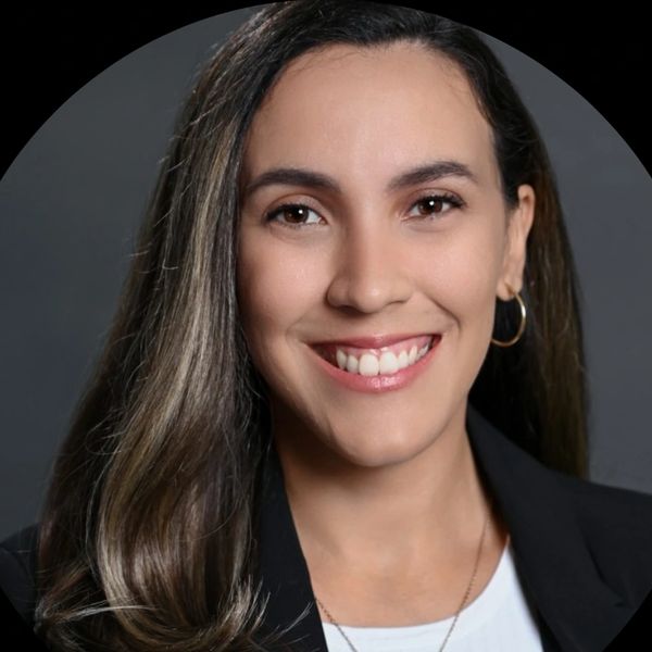 Professional woman smiling with long hair and hoop earrings.