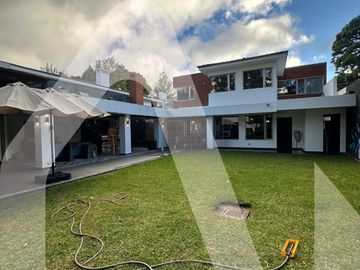 Modern two-story house with spacious green lawn and patio area.