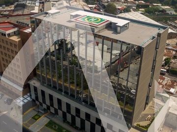 Modern office building with a rooftop helipad in an urban area.