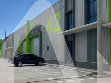 Black pickup truck parked outside modern industrial building with green accents.