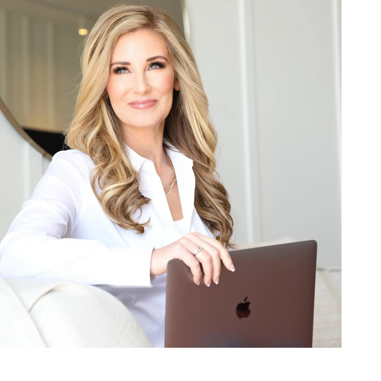 Woman smiling with her hand resting on her Apple MacBook Pro .