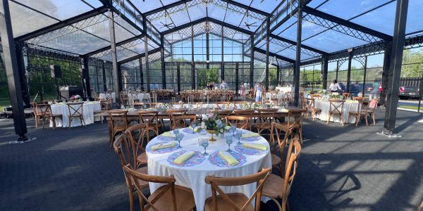 Elegant glass-walled event space with round tables set for a gathering.