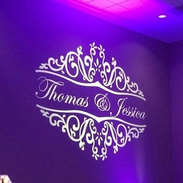Elegant wall decoration with the names Thomas and Jessica illuminated in purple light.
