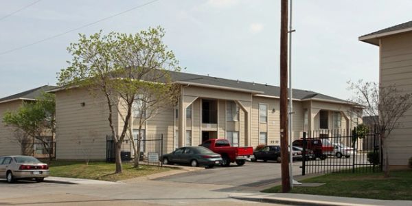 Exterior view of apartment buildings with parked cars.
