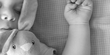 Baby sleeping in a cot with rabbit comforter