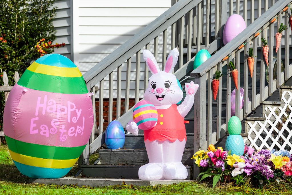 Inflatable Easter decorations including a bunny and eggs on a house porch.