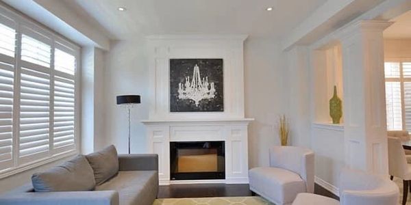 Modern living room with fireplace, gray sofa, and chandelier artwork.