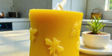Yellow candle with bee decorations on a kitchen counter.