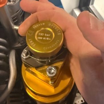 Hand holding a yellow pressure regulator cap.