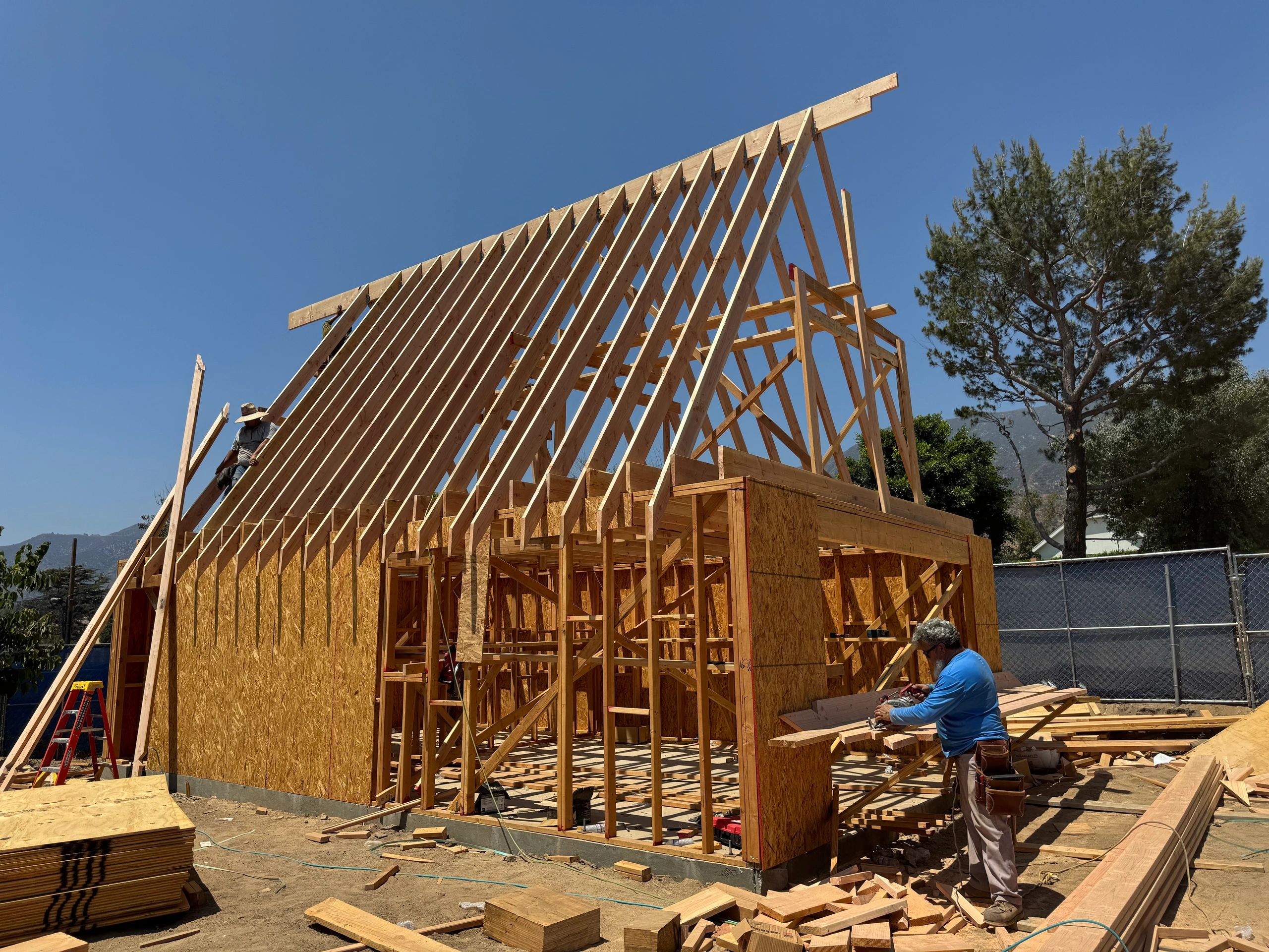 Wooden frame construction of a house under a clear sky.