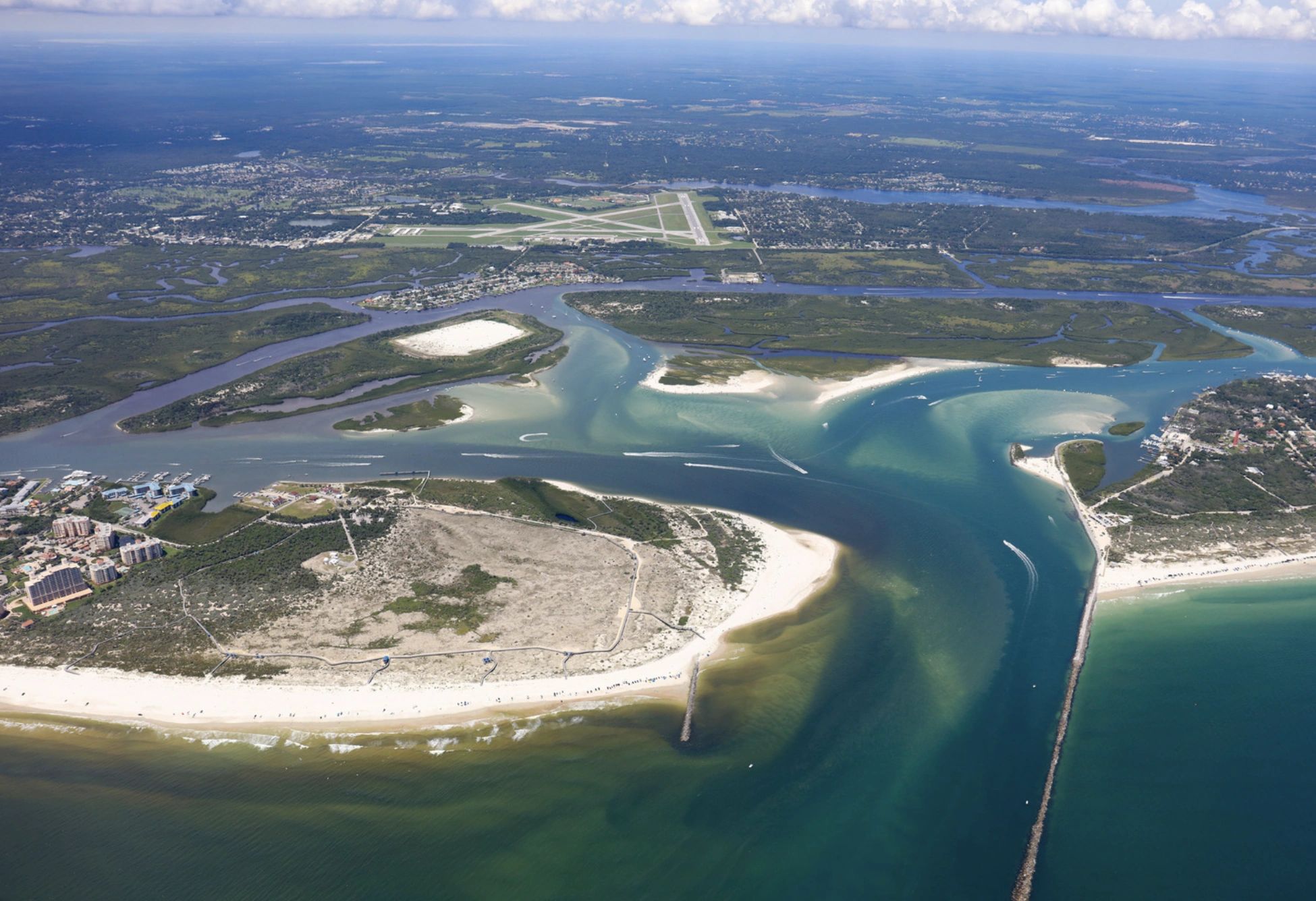 Aerial view of a coastal landscape with water channels and an airport runway.