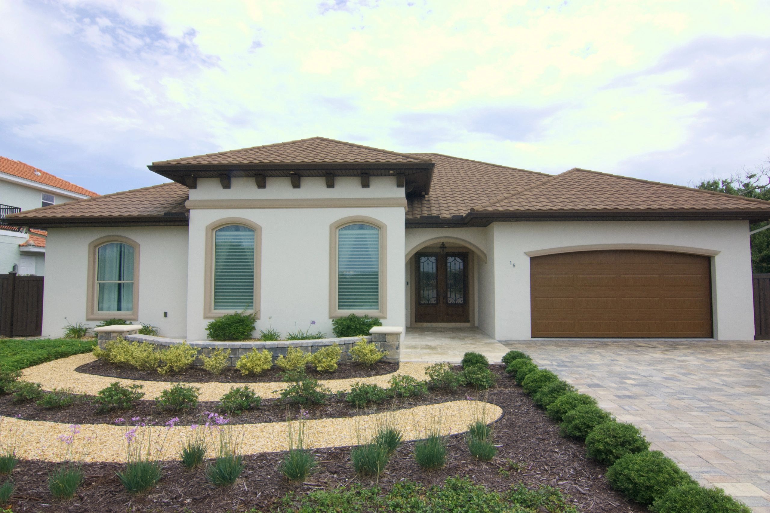 Modern house with a brown tiled roof and landscaped front yard.
