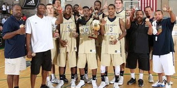Basketball team celebrating with a trophy on the court.