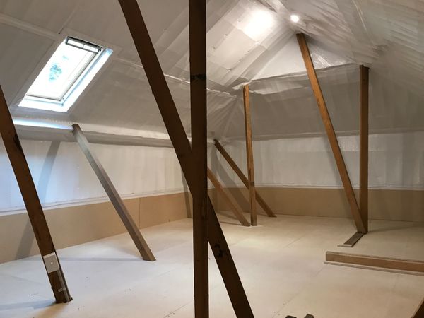 An unfinished attic space with exposed wooden beams and a skylight window.