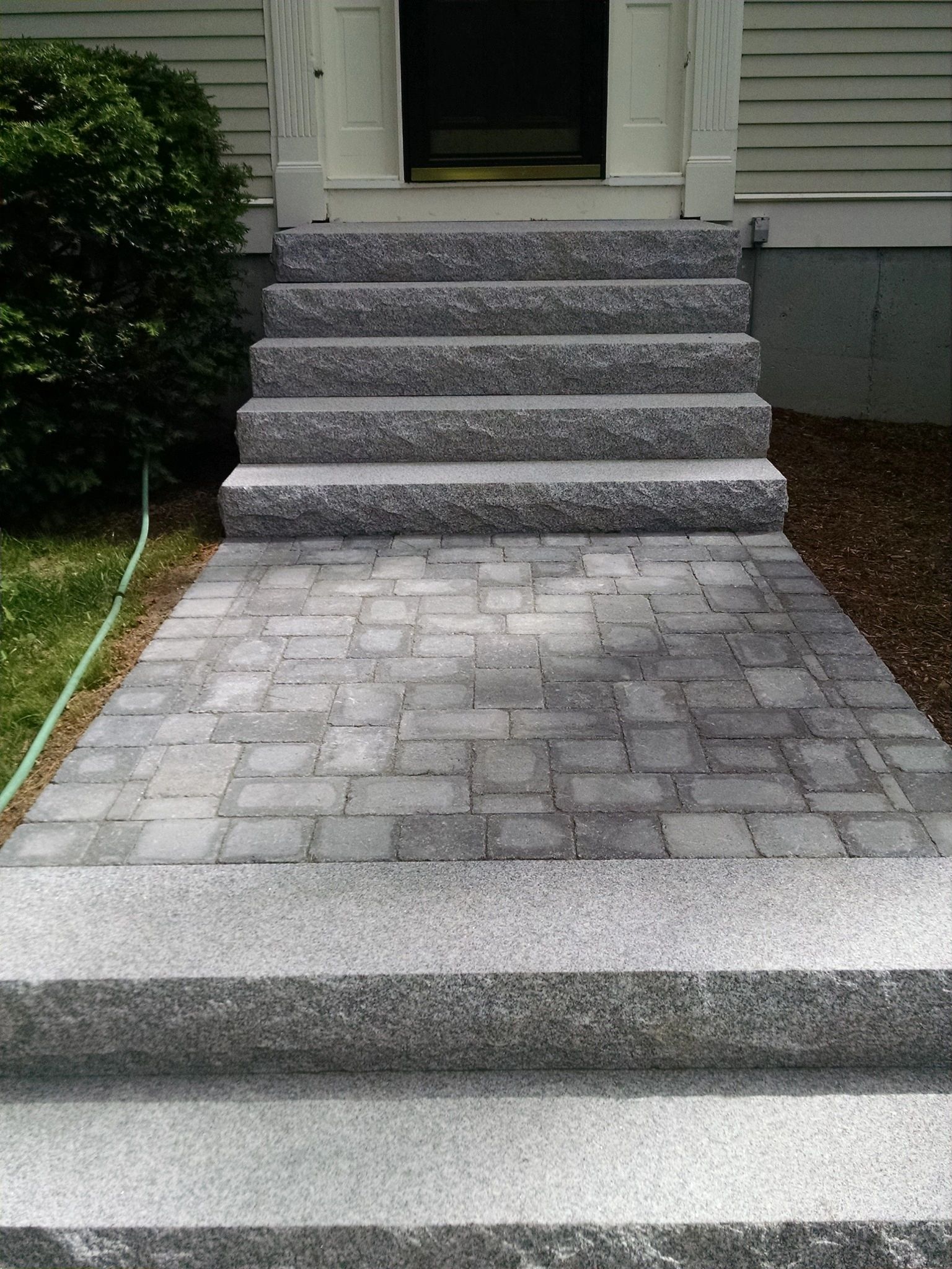 Stone steps leading to a house entrance with a paved walkway