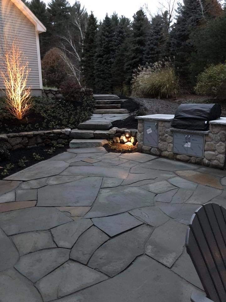 Outdoor stone patio with built-in grill and pathway lighting