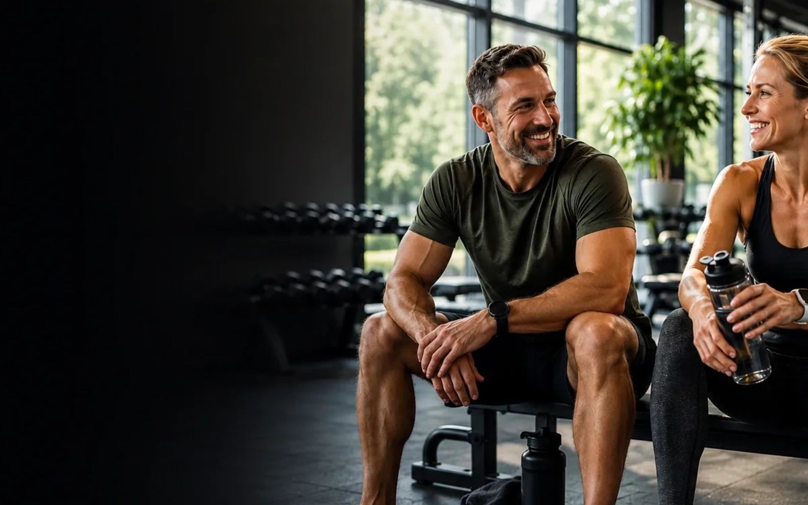 Two people smiling and resting in a gym.