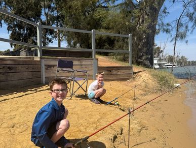 boy with a disability sitting with a fishing rod at the murray river