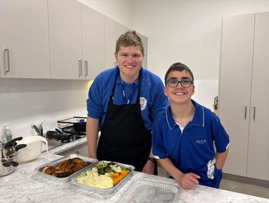 disability support worker with young teenager in after school kids club cooking