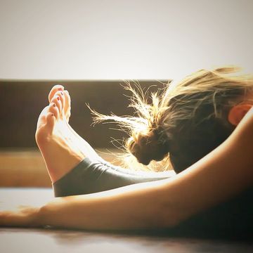 Personne pratiquant le yoga avec le soleil en arrière-plan.