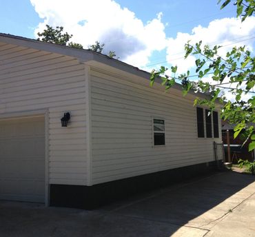 White single-story house with a garage and driveway under a blue sky.