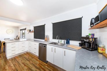 Modern kitchen with white cabinets and dark window blinds.