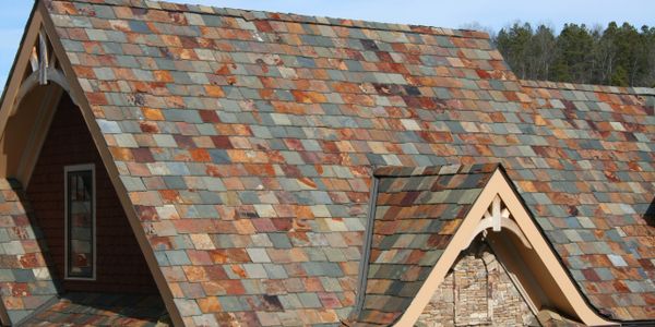 House roof with multicolored slate tiles under a clear sky.
