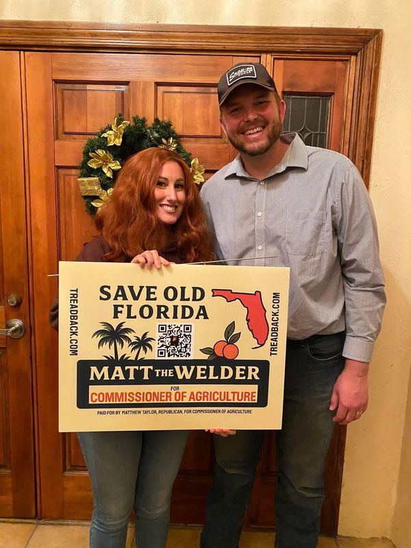 Two people holding a campaign sign for Matt the Welder for Florida Commissioner of Agriculture.