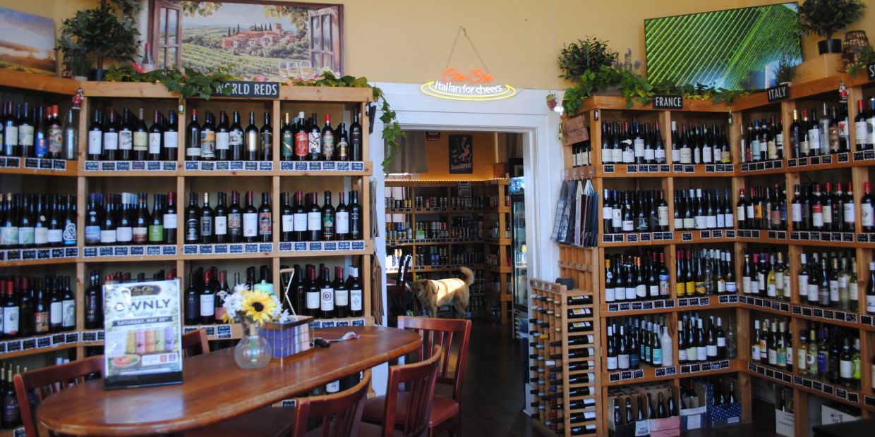Wine shop with wooden shelves and a table in the center.