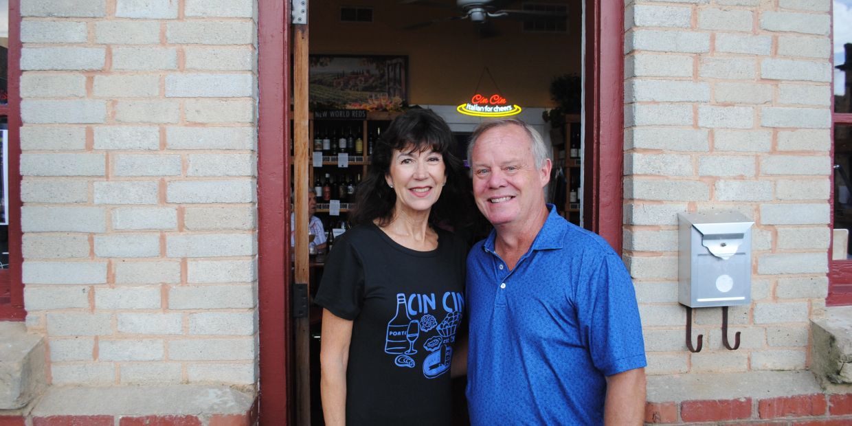Smiling couple posing outside brick building doorway.