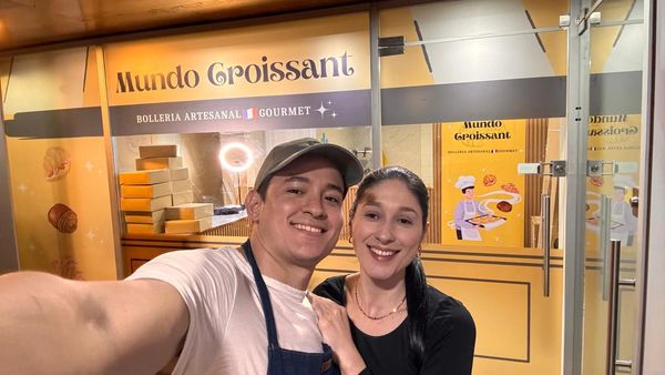 A smiling couple takes a selfie in front of Mundo Croissant bakery.