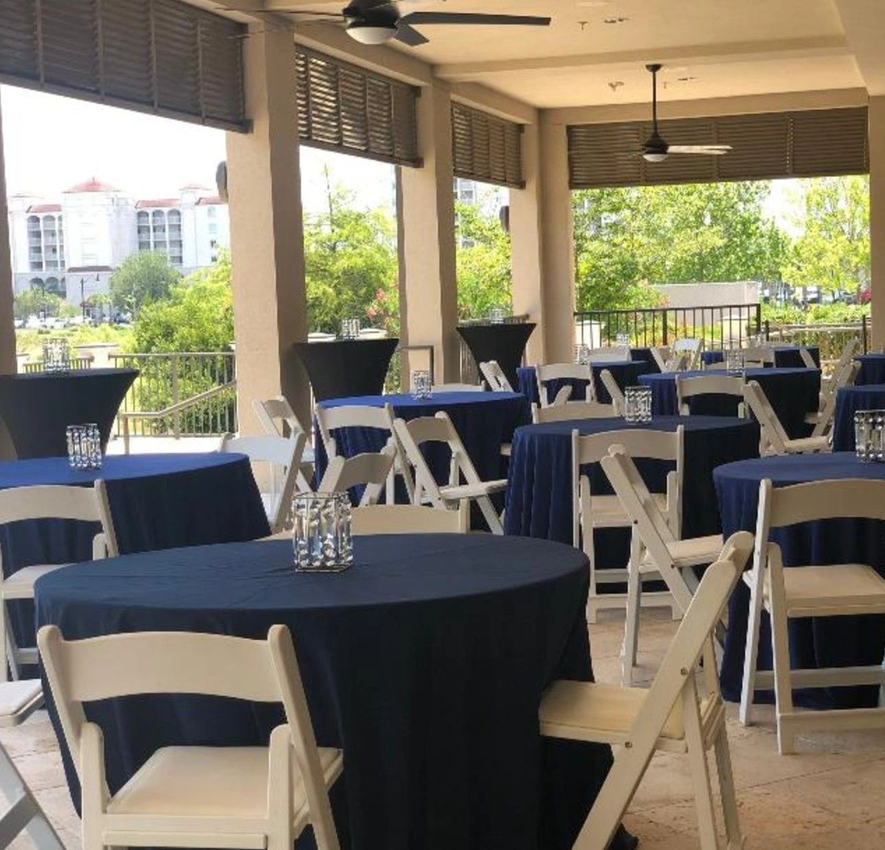 Outdoor event space with navy-covered tables and white chairs.