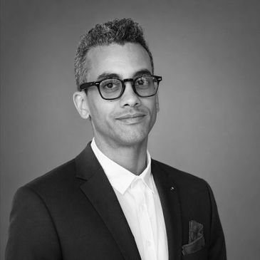 Professional black and white portrait of a man in glasses and suit.