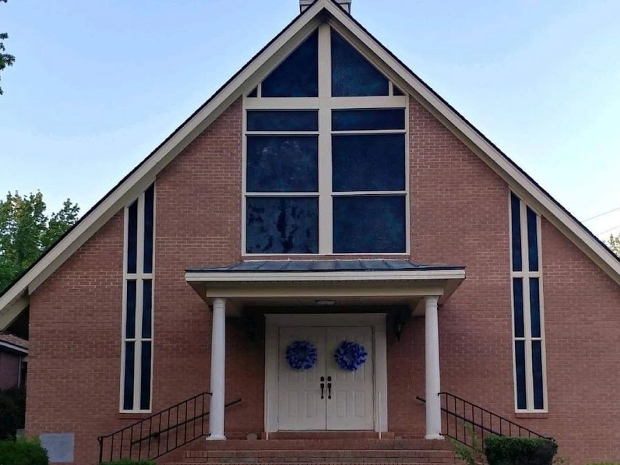 Brick church with cross-shaped window and twin doors.