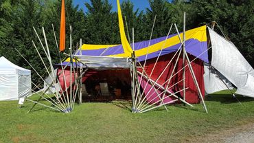 Colorful tent with many poles on a grassy field.