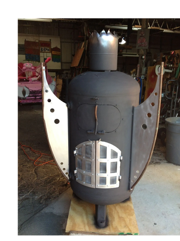 Custom metal stove shaped like a robot with a crown in a workshop.