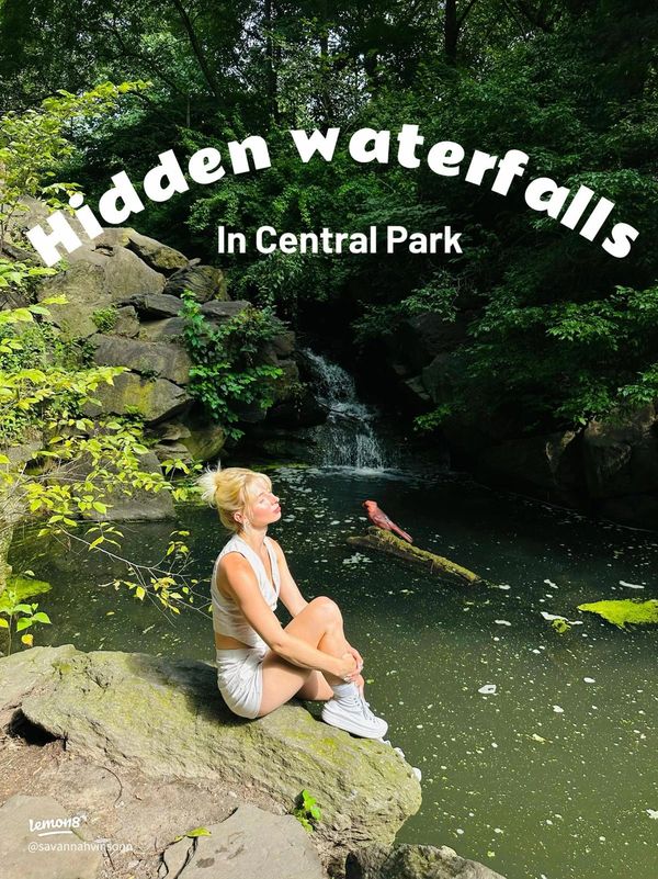 Woman in white sitting by a hidden waterfall in Central Park.