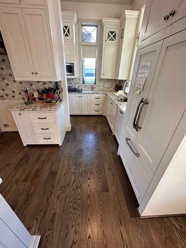 Hardwood floor installation in a Lafayette, LA kitchen with custom oak flooring and white cabinetry